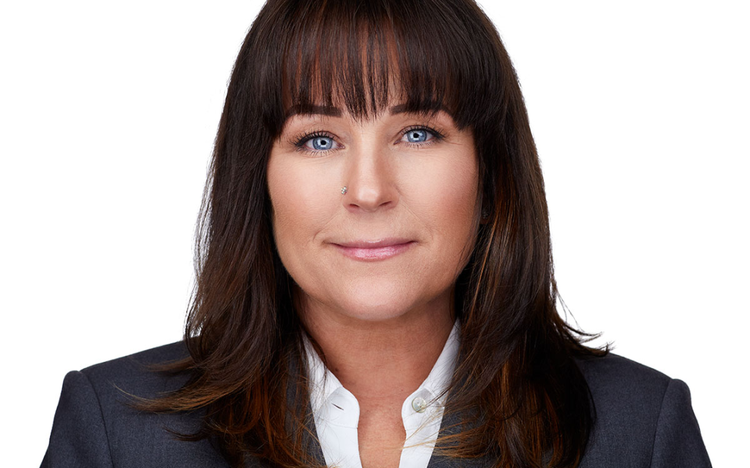 Professional female executive headshot in Los Angeles wearing a dark gray suite and smiling